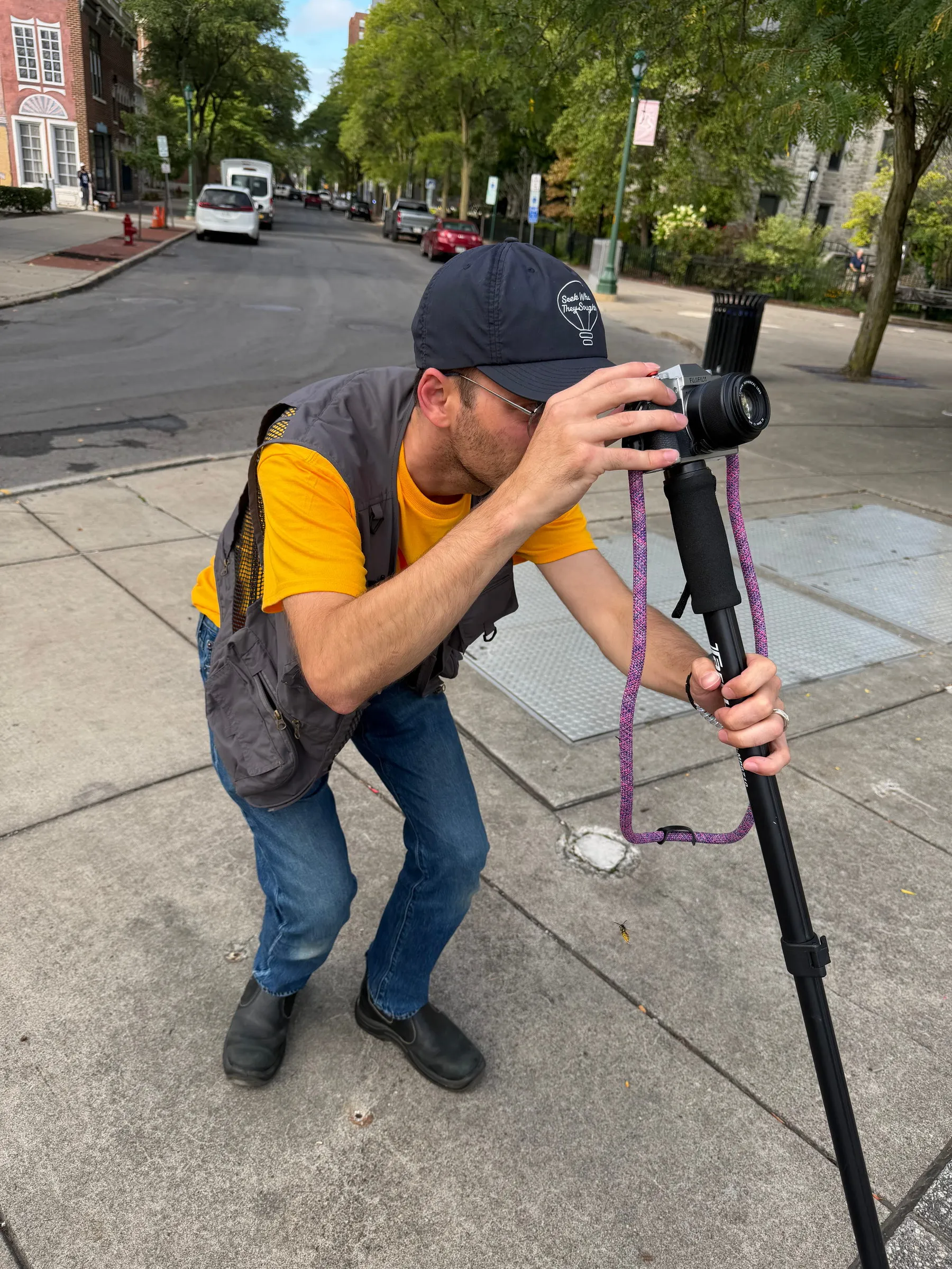 A team member in a yellow shirt crouching to shoot with a camera on a monopod