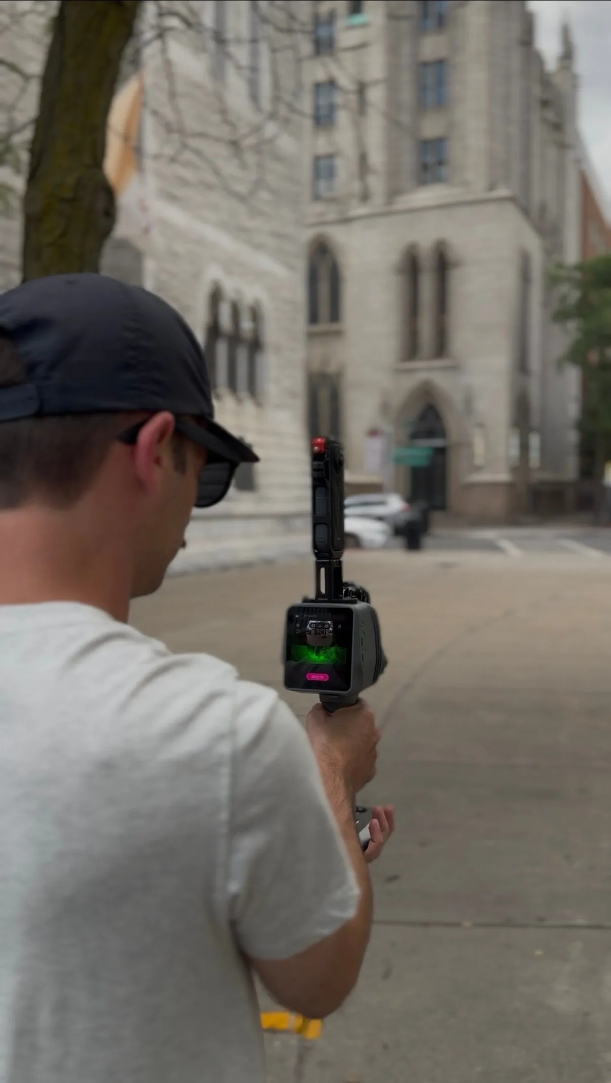 A team member holding a handheld scanner on the sidewalk beside the cathedral