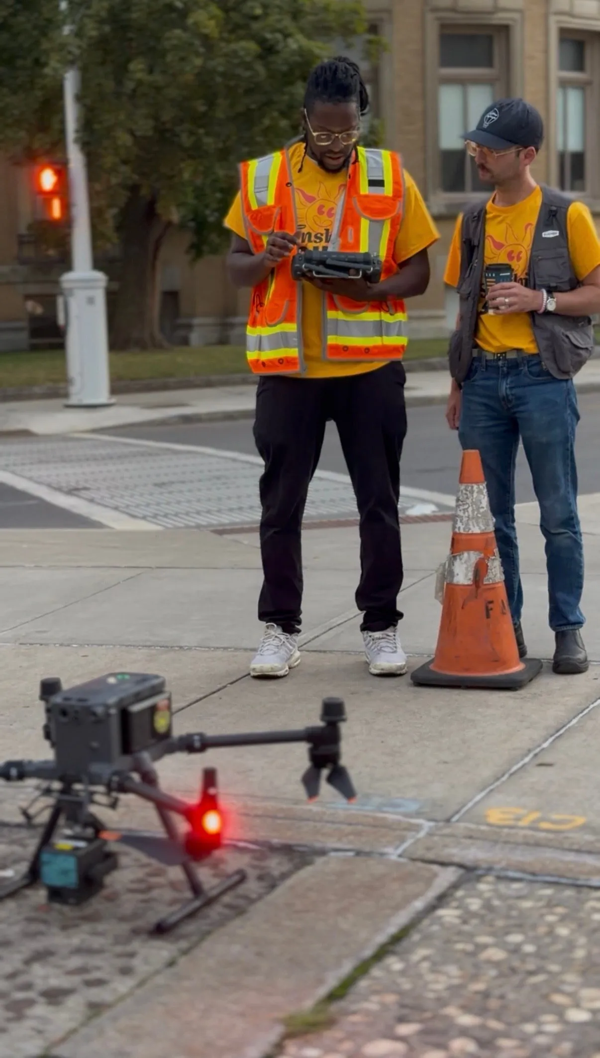 Two team members, one holding a drone controller, standing over a drone on the pavement